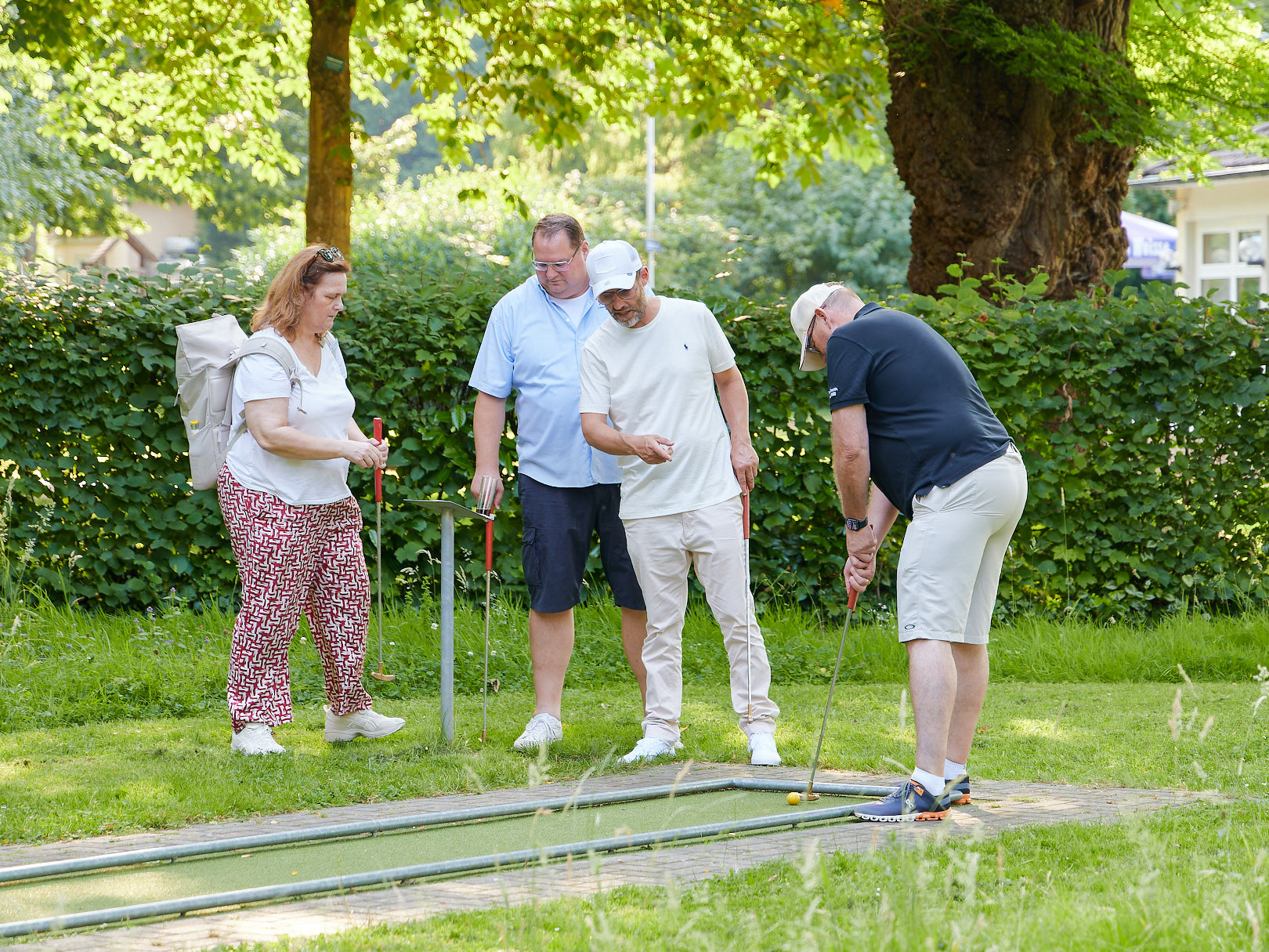 Menschen beim Minigolfspiel und ein Spieler erklärt einem anderen Spiele die Regeln