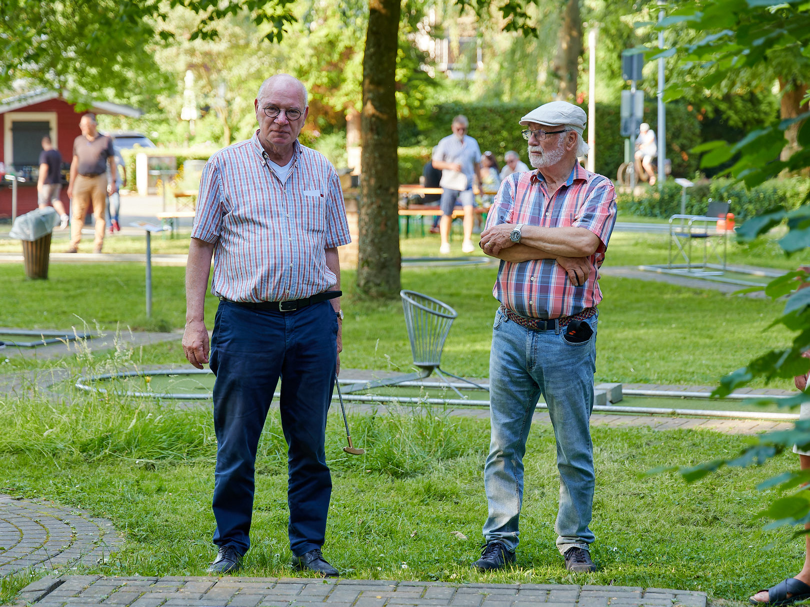 Zwei Minigolfspieler die neben einer Minigolfbahn stehen