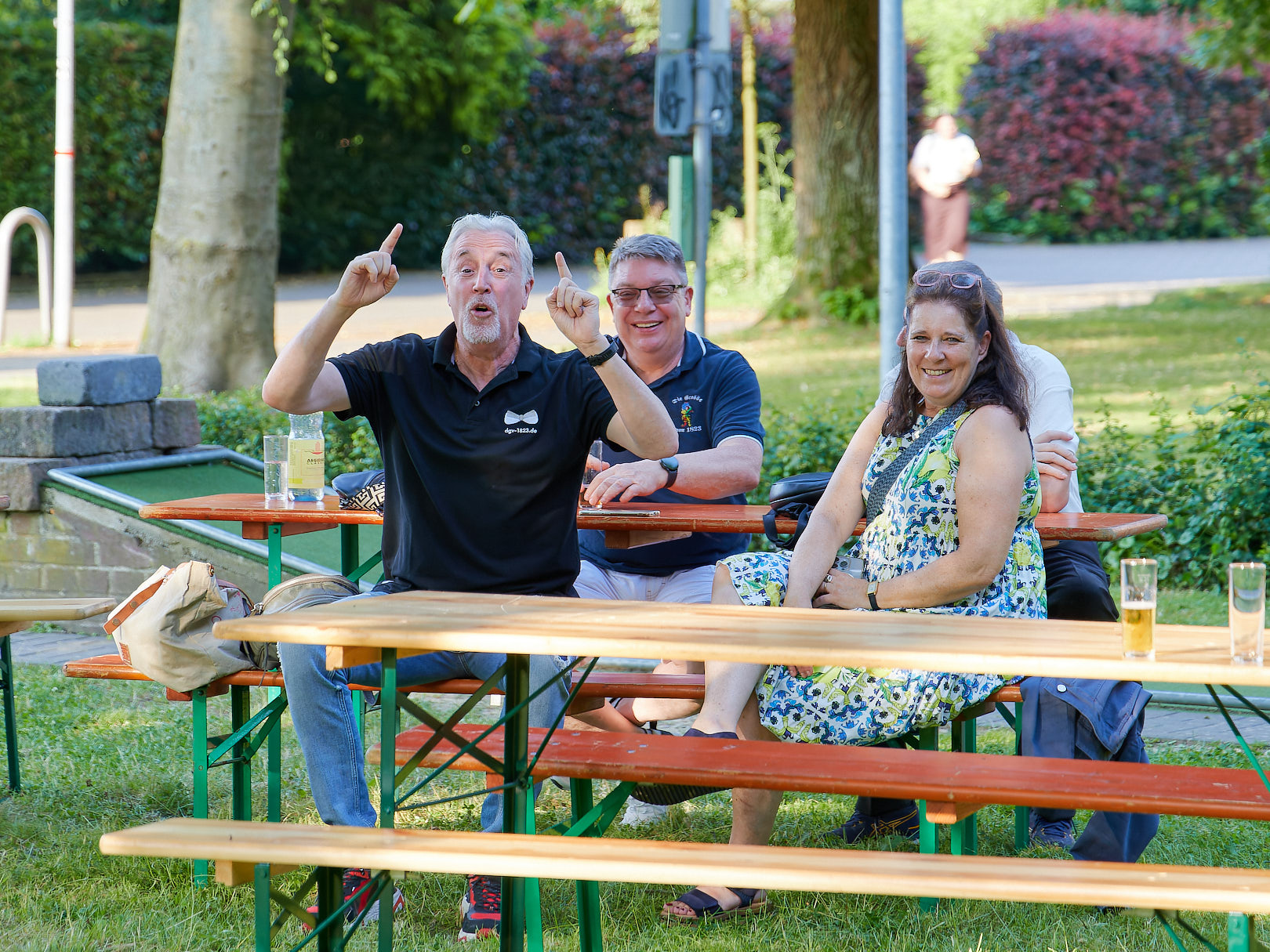 Menschen sitzen auf Bänken am Minigolfplatz